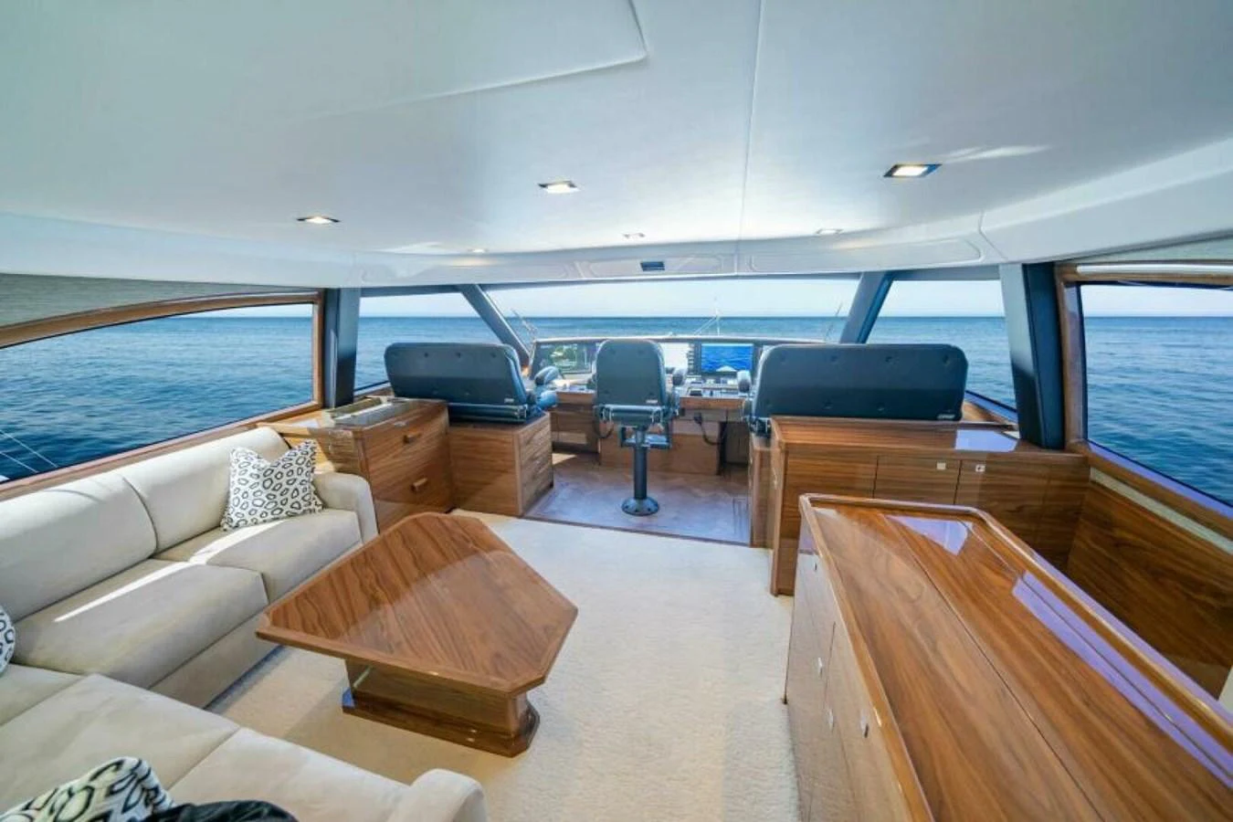 The helm area features expansive windows offering panoramic ocean views, complemented by luxurious wood finishes and comfortable seating. aboard 2027 VIKING 90SB Yacht for Sale