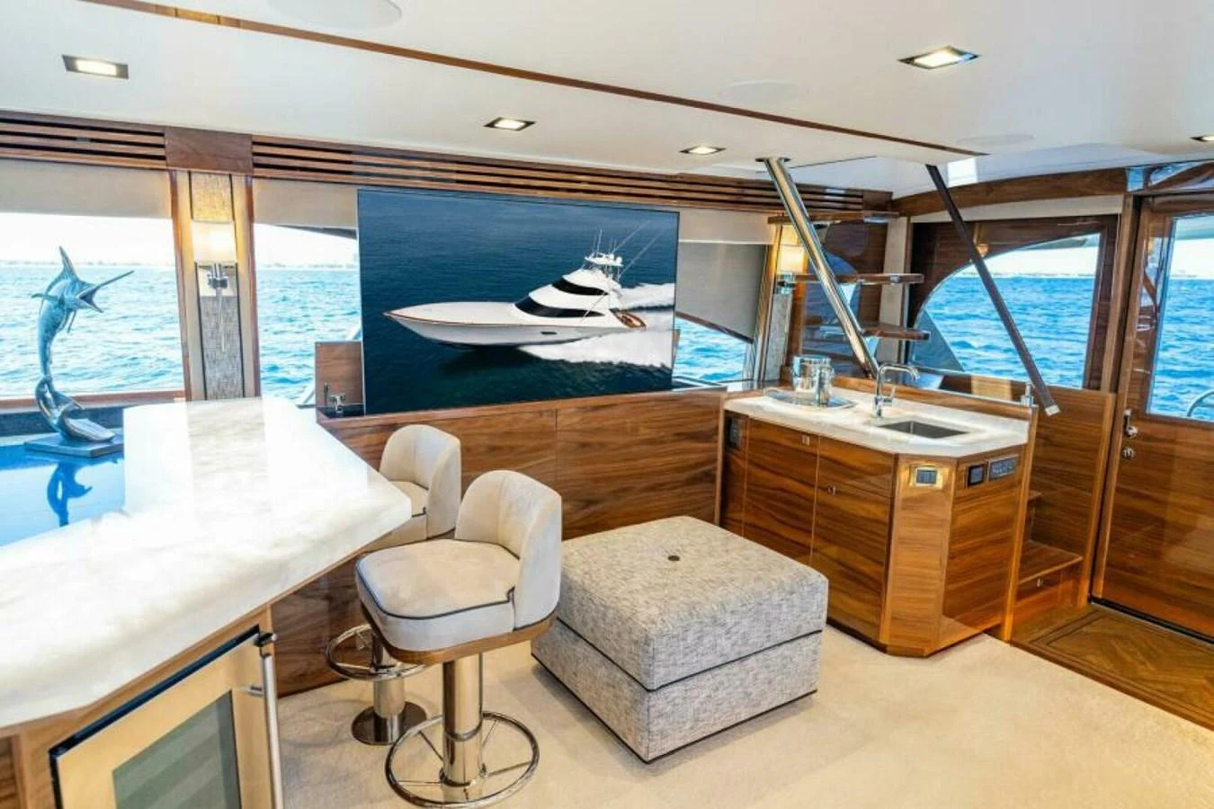 The salon features luxurious seating, a bar area, and large windows offering stunning ocean views. aboard 2027 VIKING 90SB Yacht for Sale