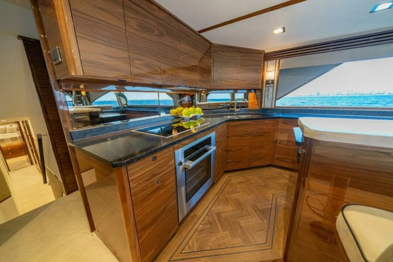 The yacht's galley features sleek wooden cabinetry, modern appliances, and a scenic view through large windows. aboard 2027 VIKING 90SB Yacht for Sale