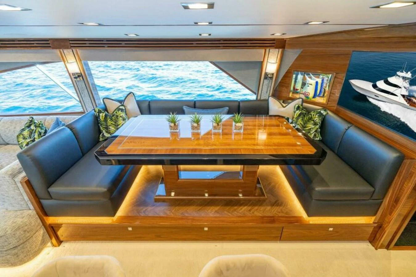 The yacht's dining area features a luxurious wooden table surrounded by plush seating, with large windows offering stunning ocean views. aboard 2027 VIKING 90SB Yacht for Sale