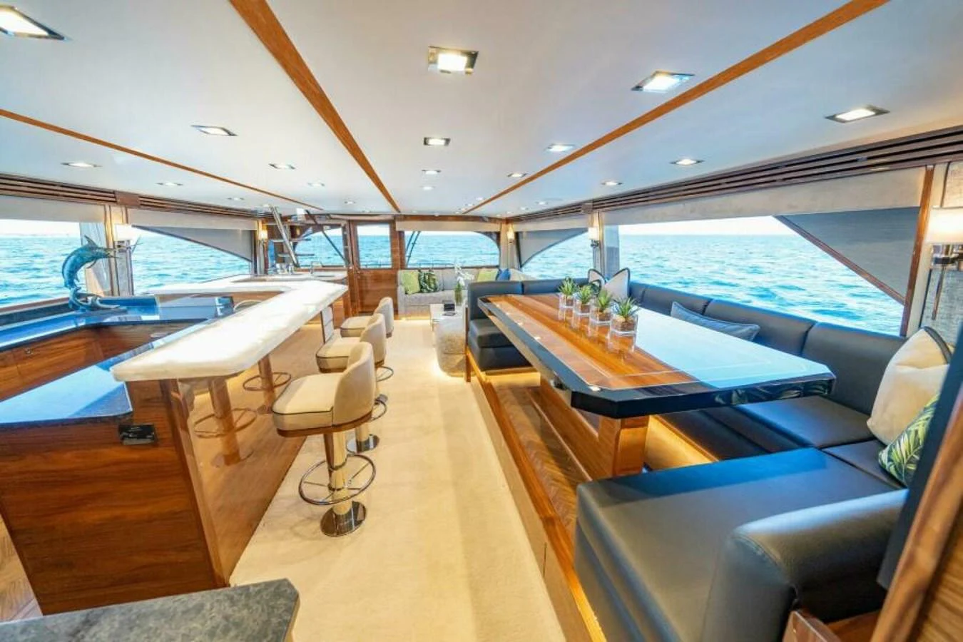 The salon features a spacious seating area with panoramic windows offering stunning ocean views. aboard 2027 VIKING 90SB Yacht for Sale