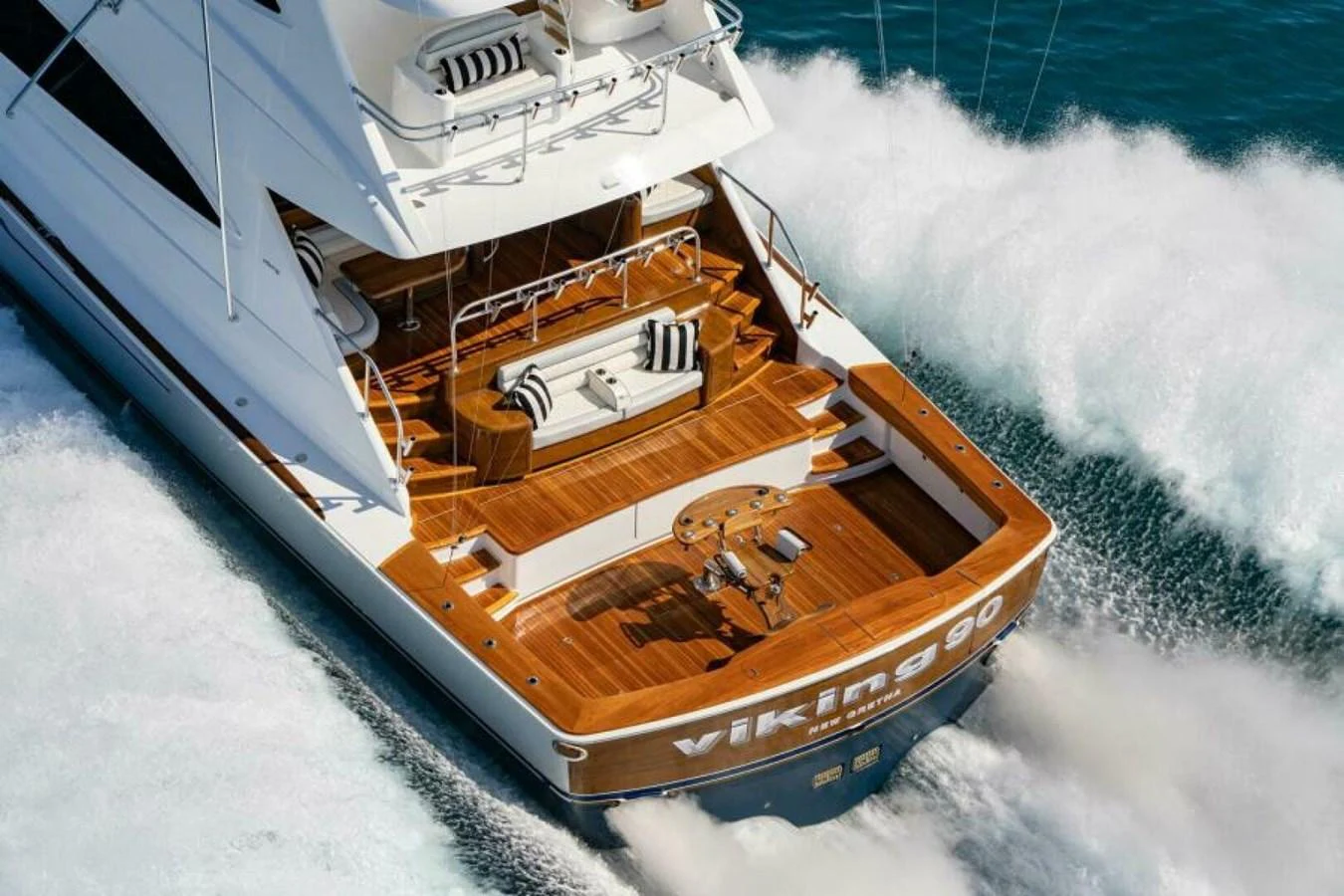 The yacht's aft deck features elegant wooden flooring and comfortable seating, perfect for relaxation while cruising. aboard 2027 VIKING 90SB Yacht for Sale