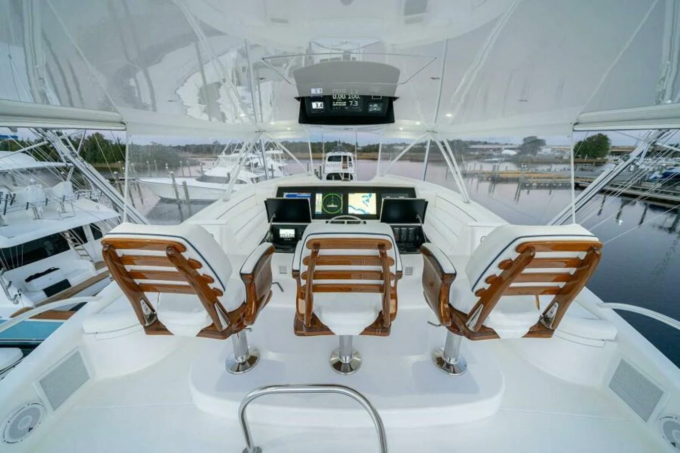 The helm station features three luxurious captain's chairs with a panoramic view of the marina. aboard 2027 VIKING 90C Yacht for Sale