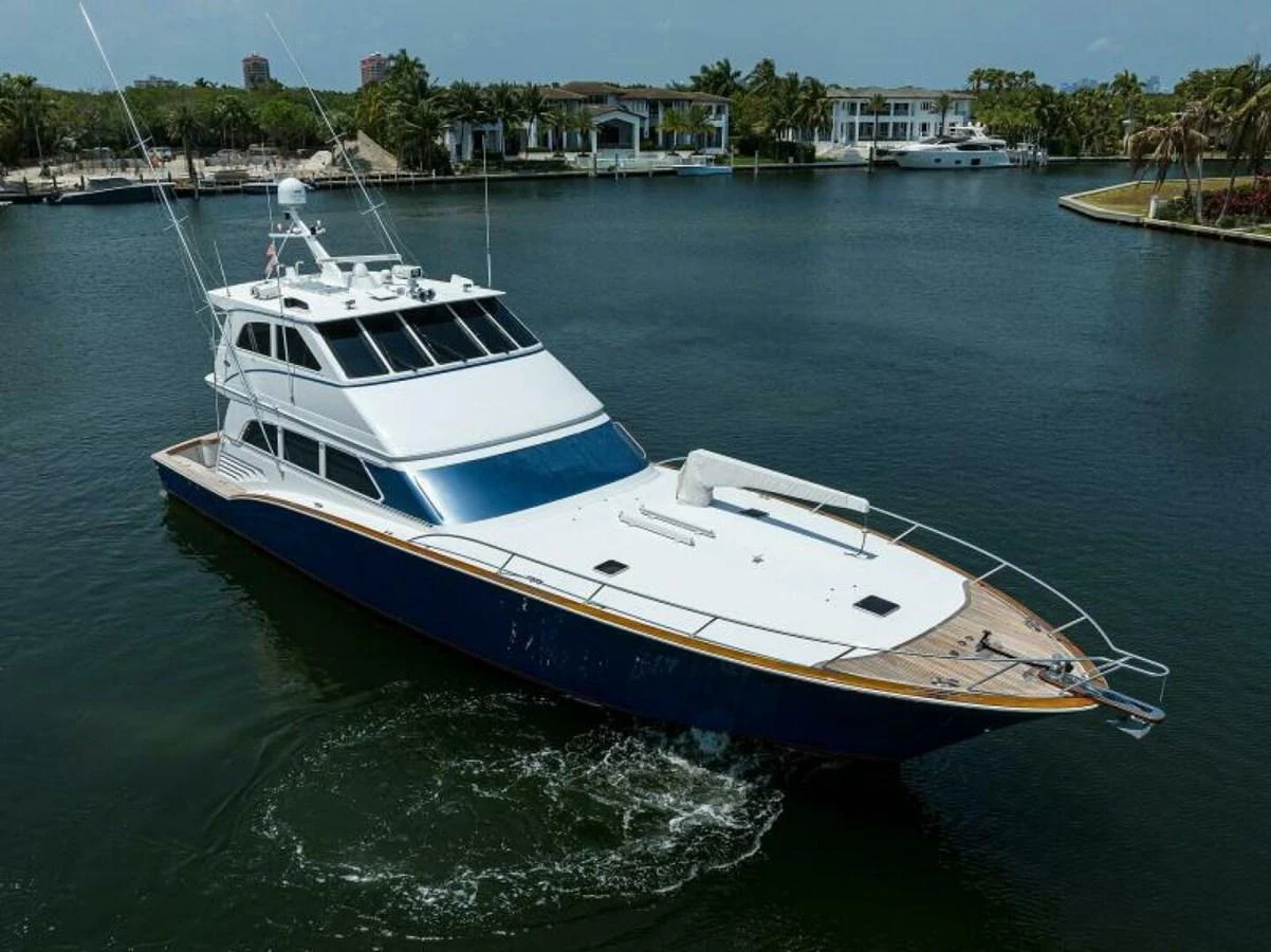 A sleek yacht glides through calm waters near a luxurious waterfront community. aboard JUNIOR Yacht for Sale