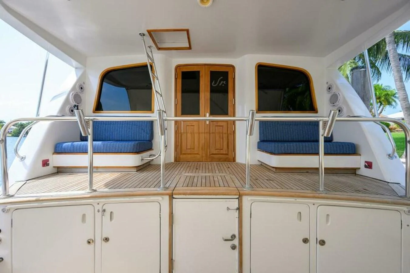 The aft deck features comfortable seating and a polished wooden door leading to the interior. aboard JUNIOR Yacht for Sale