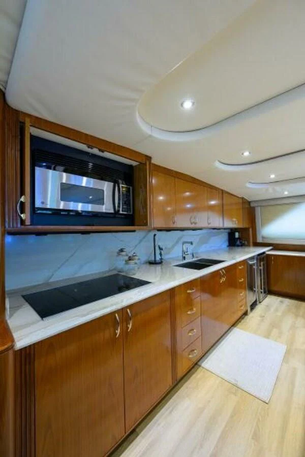 The galley features sleek wooden cabinetry and modern appliances, creating a warm and functional space. aboard JUNIOR Yacht for Sale