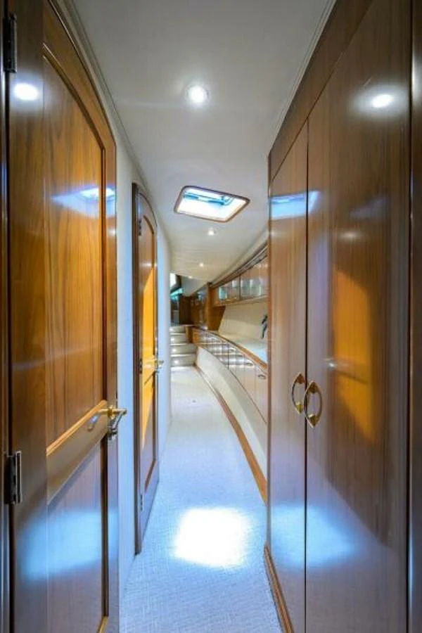 A polished wood-paneled hallway leads to the yacht's interior spaces, illuminated by natural light from a skylight. aboard JUNIOR Yacht for Sale