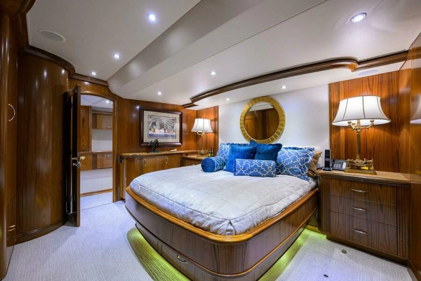 The master stateroom features a luxurious bed with elegant wooden finishes and ambient lighting. aboard JUNIOR Yacht for Sale