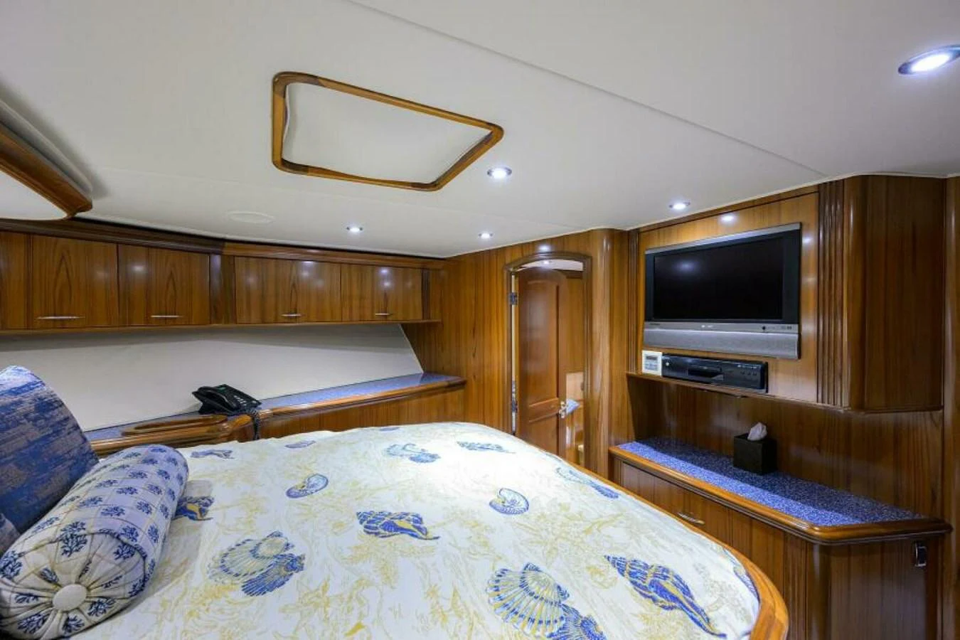 The stateroom features a cozy bed with patterned linens, wooden cabinetry, and a mounted television for entertainment. aboard JUNIOR Yacht for Sale