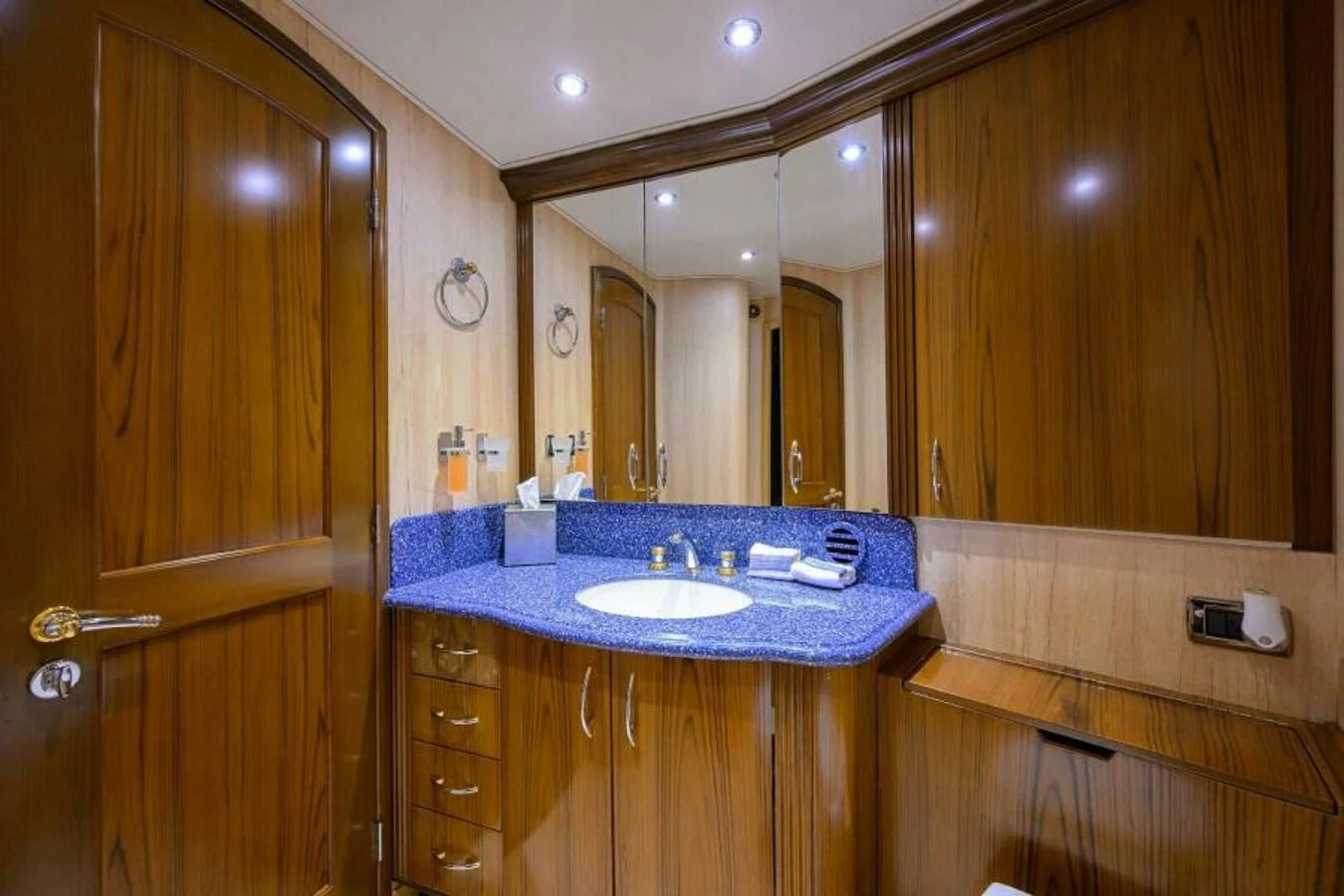 The yacht's bathroom features elegant wooden cabinetry and a sleek blue countertop. aboard JUNIOR Yacht for Sale