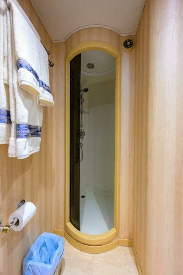 A compact and well-appointed yacht bathroom with a shower and neatly arranged towels. aboard JUNIOR Yacht for Sale