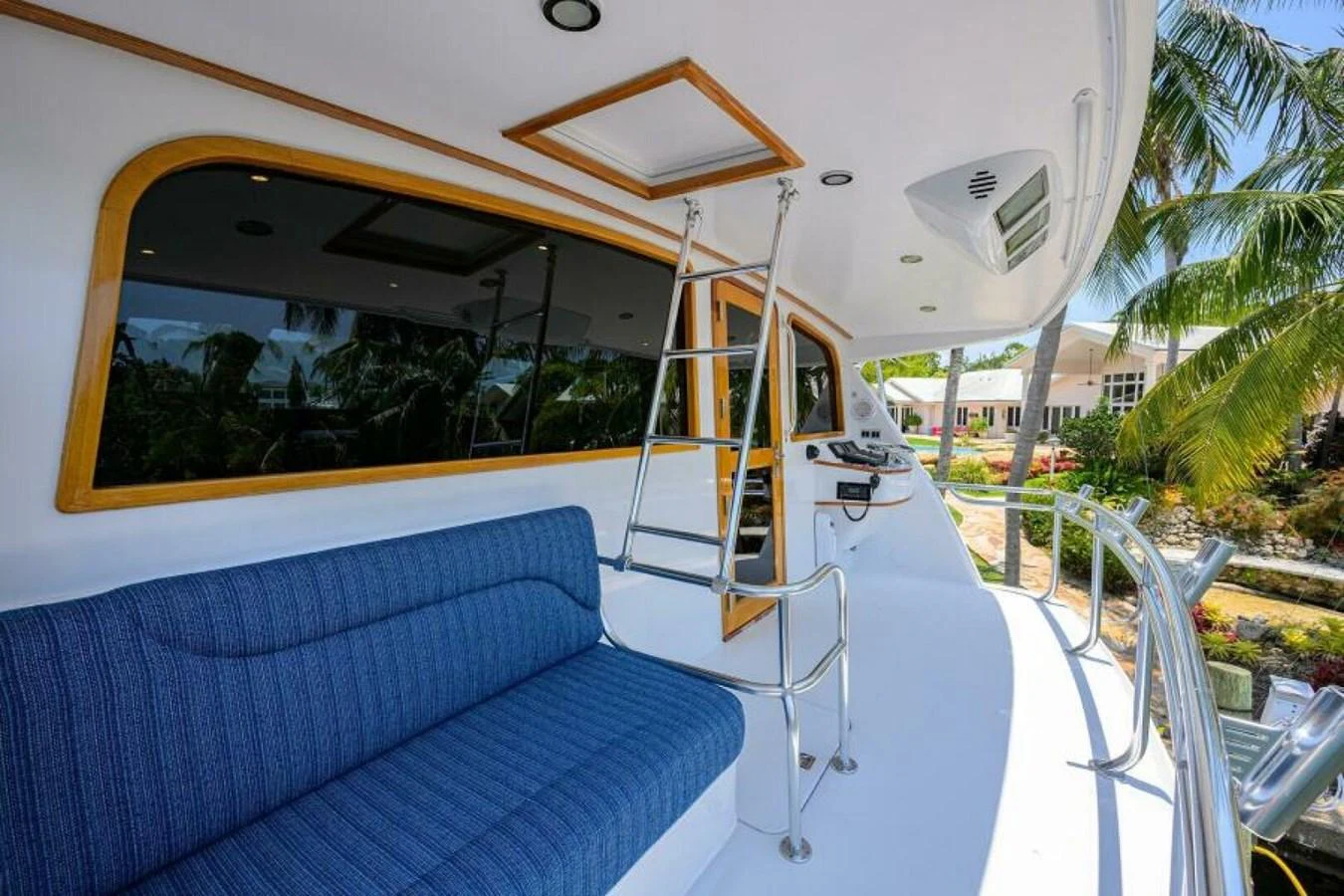 The side deck features a comfortable blue cushioned seating area with a view of the surroundings. aboard JUNIOR Yacht for Sale