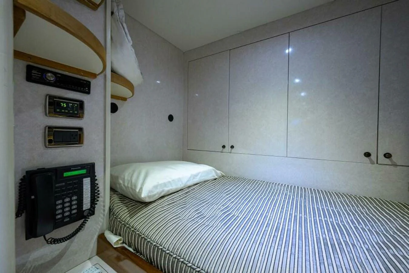 The crew cabin features a comfortable bed with built-in storage and essential communication equipment. aboard JUNIOR Yacht for Sale