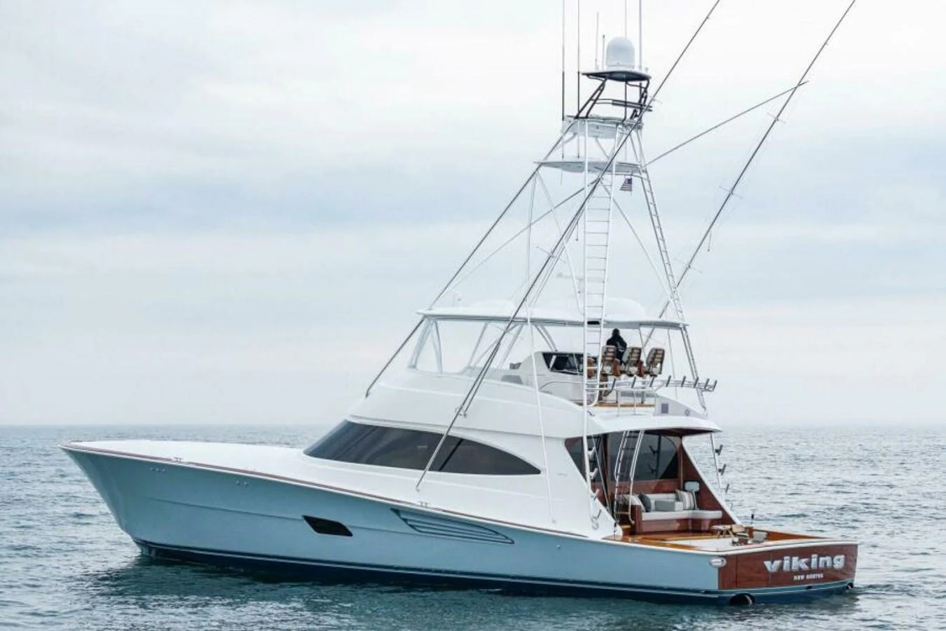 A sleek yacht with a spacious aft deck and a prominent tower, cruising on calm waters. aboard 2027 VIKING 82C Yacht for Sale