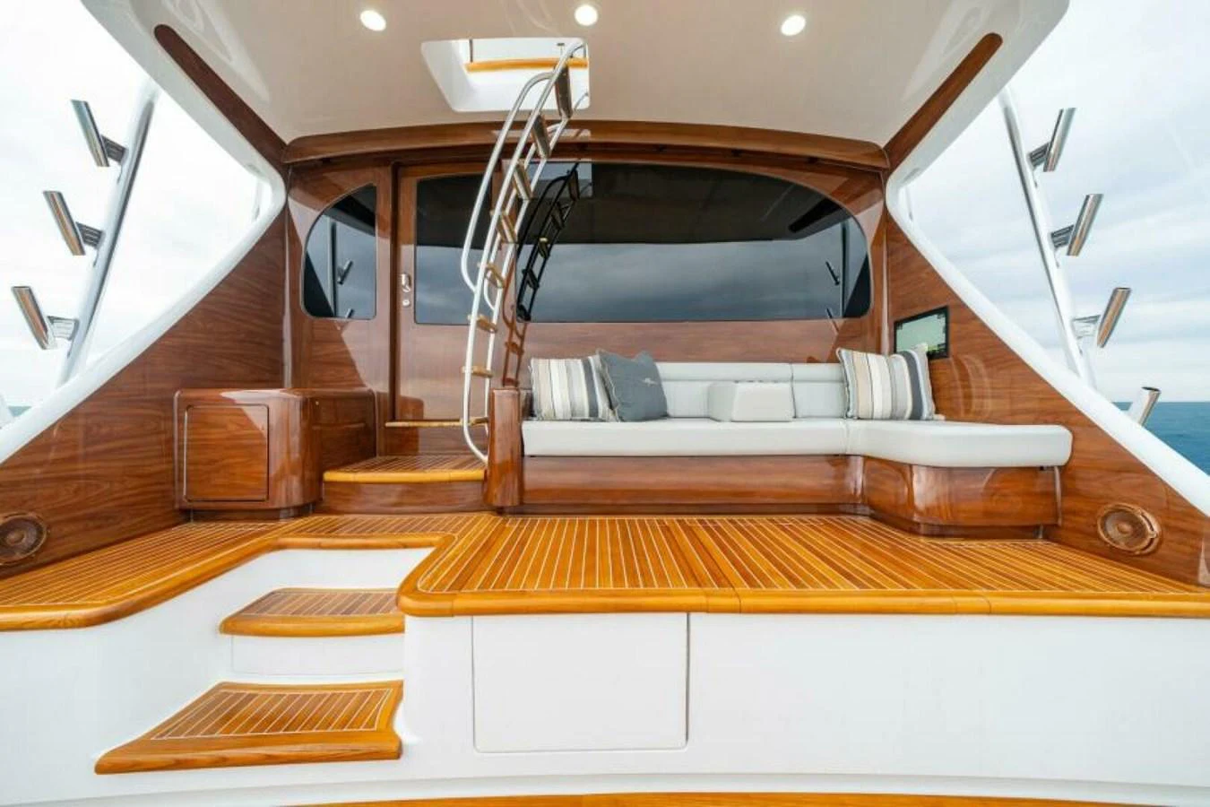 The aft deck features a stylish seating area with wooden accents and a modern staircase leading to the upper deck. aboard 2027 VIKING 82C Yacht for Sale