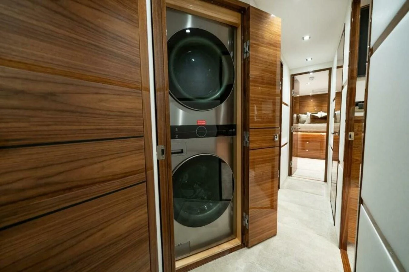 The yacht features a sleek and modern laundry area with stacked washer and dryer units. aboard 2027 VIKING 82C Yacht for Sale