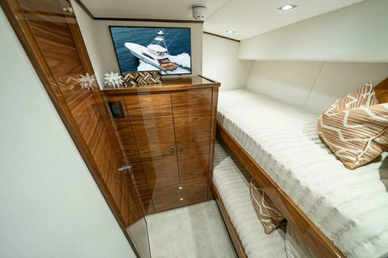 A cozy guest cabin with twin bunk beds and a television displaying a yacht. aboard 2027 VIKING 82C Yacht for Sale
