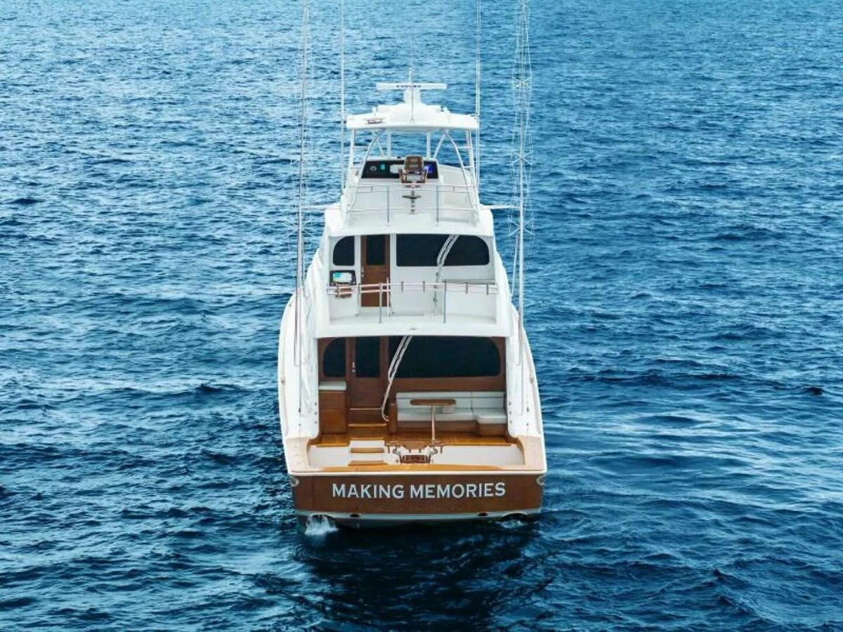 A yacht named 'Making Memories' is seen from the rear, cruising on the open sea. aboard 2027 VIKING 82SB Yacht for Sale