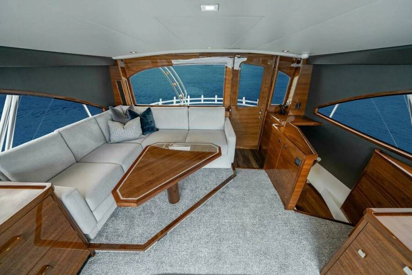 The salon features elegant wood finishes and a comfortable seating area with a stunning view of the ocean. aboard 2027 VIKING 82SB Yacht for Sale