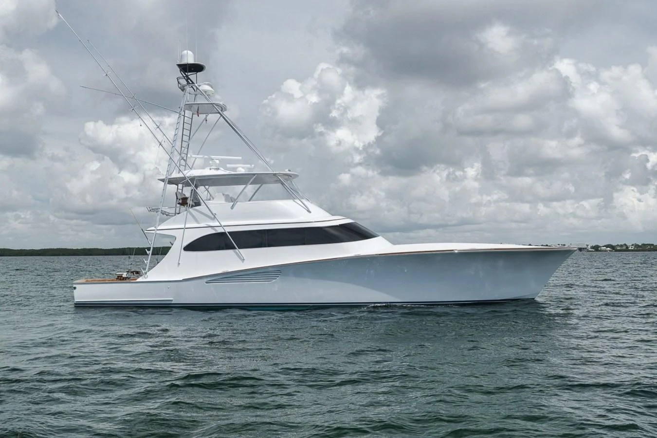 A sleek and modern yacht glides gracefully on calm waters under a cloudy sky. aboard GENESIS Yacht for Sale