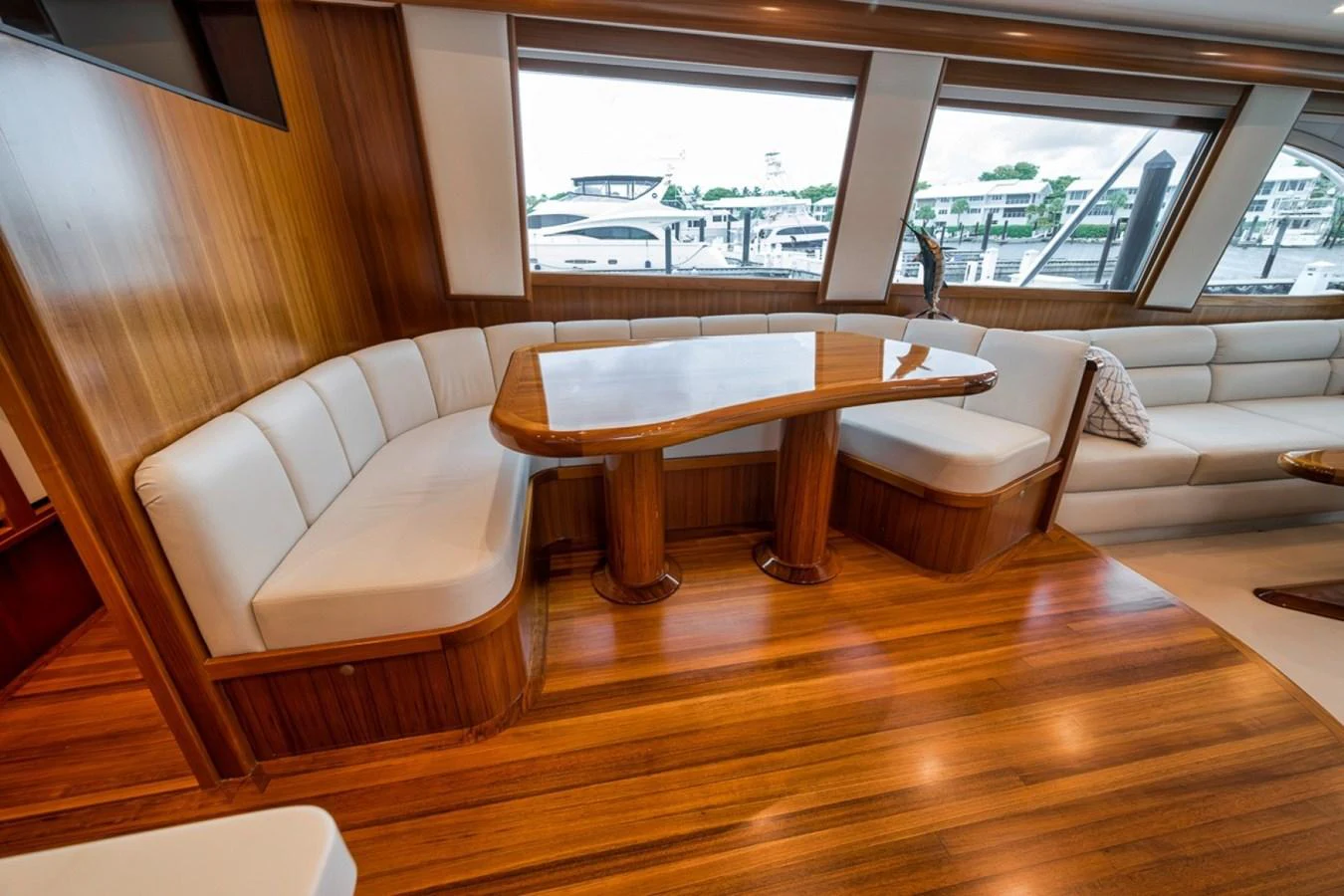 The yacht's dining area features elegant wood finishes and comfortable seating with large windows offering marina views. aboard GENESIS Yacht for Sale
