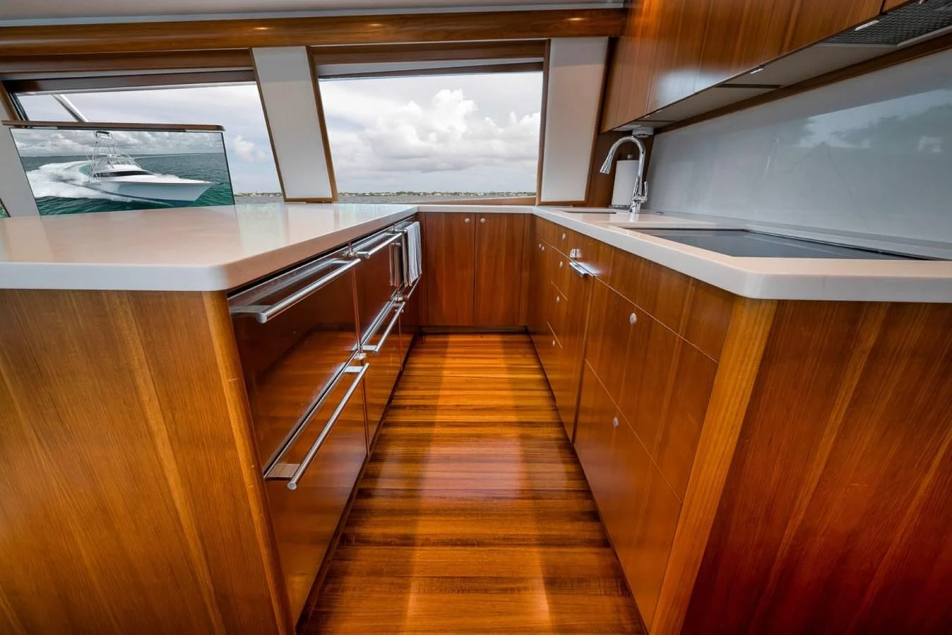 The galley features sleek wooden cabinetry and modern appliances with a view of the sea. aboard GENESIS Yacht for Sale