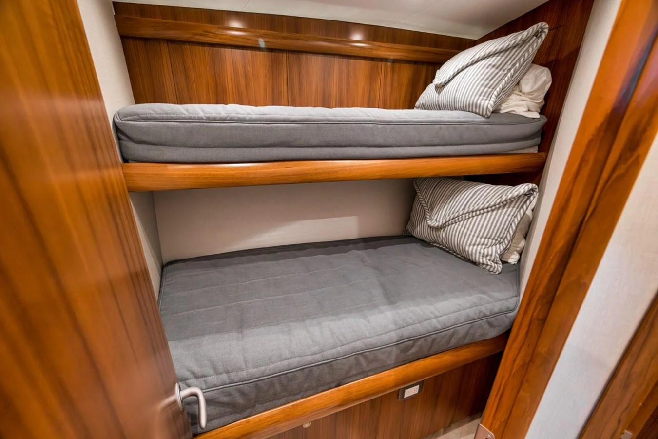 The cozy bunk room features two neatly arranged beds with striped pillows and wooden paneling. aboard GENESIS Yacht for Sale