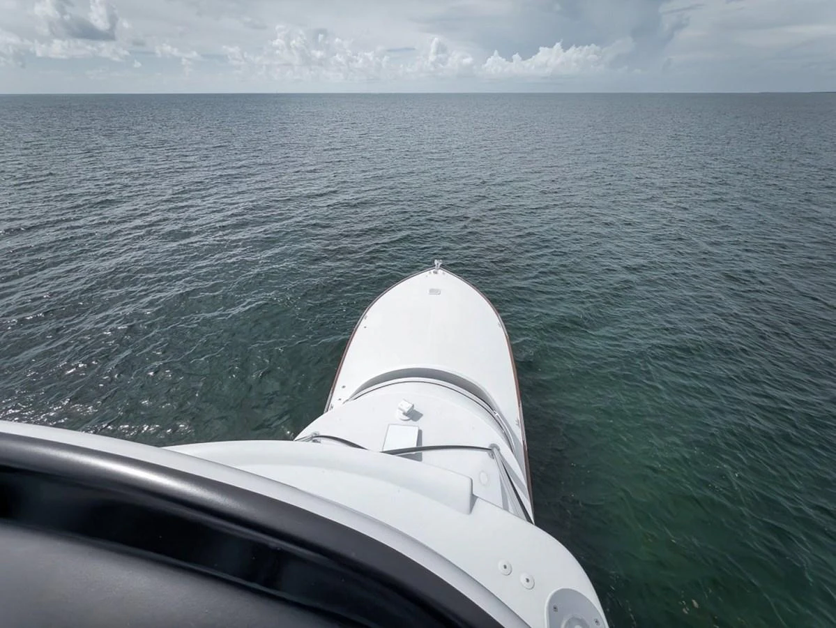 The yacht's bow cuts through the serene waters under a vast, cloudy sky. aboard GENESIS Yacht for Sale