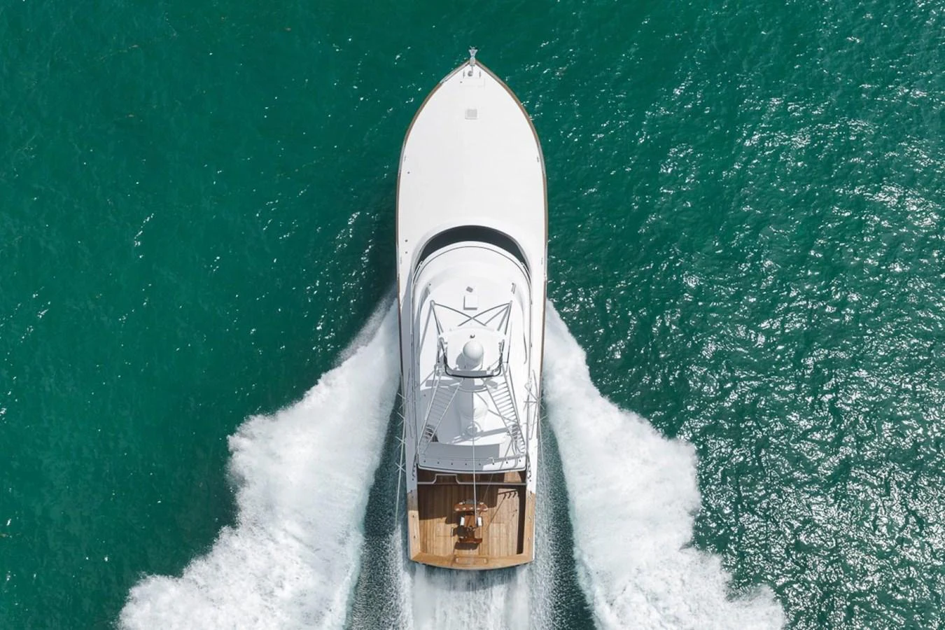 A sleek yacht cruises through vibrant turquoise waters, showcasing its elegant design from an aerial perspective. aboard GENESIS Yacht for Sale
