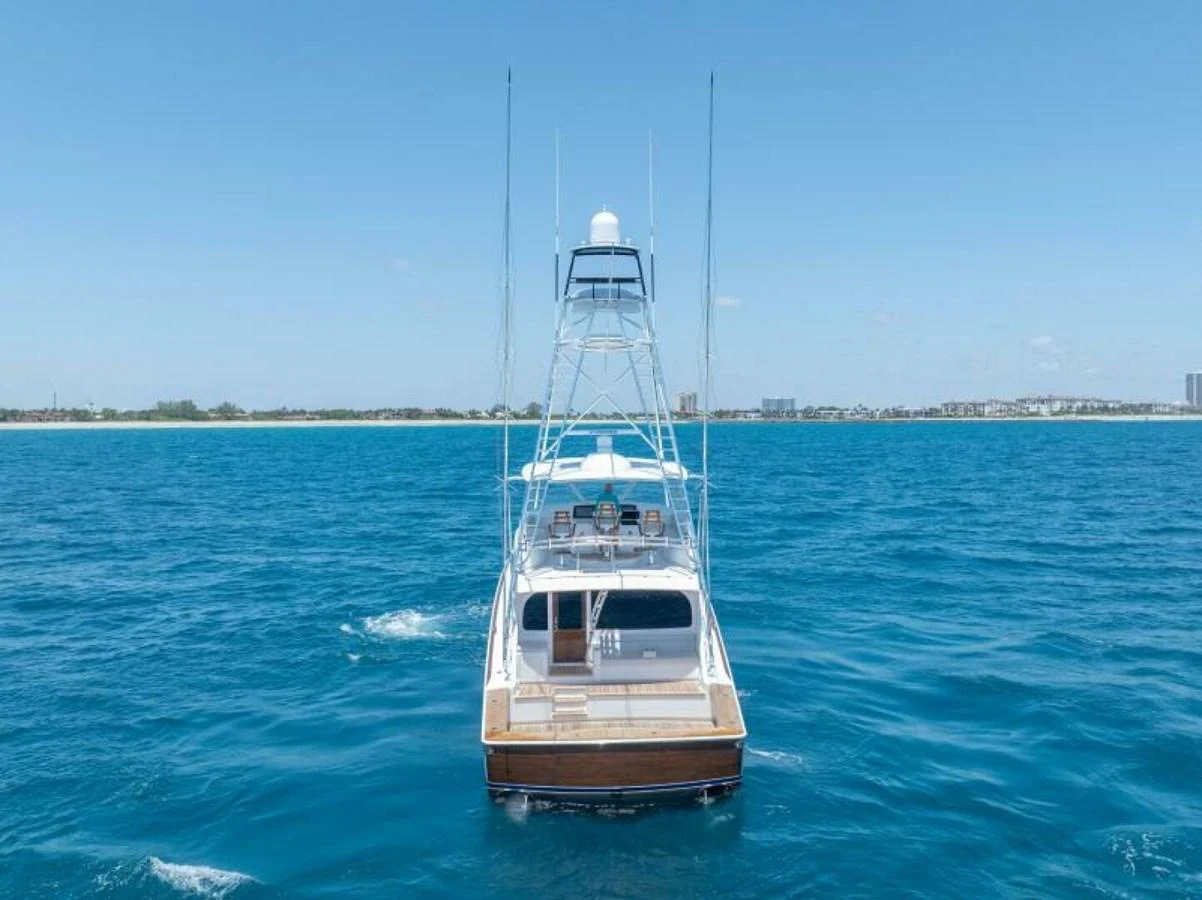 A sleek yacht cruising on clear blue waters with a view of the coastline in the background. aboard 2027 VIKING 74C Yacht for Sale