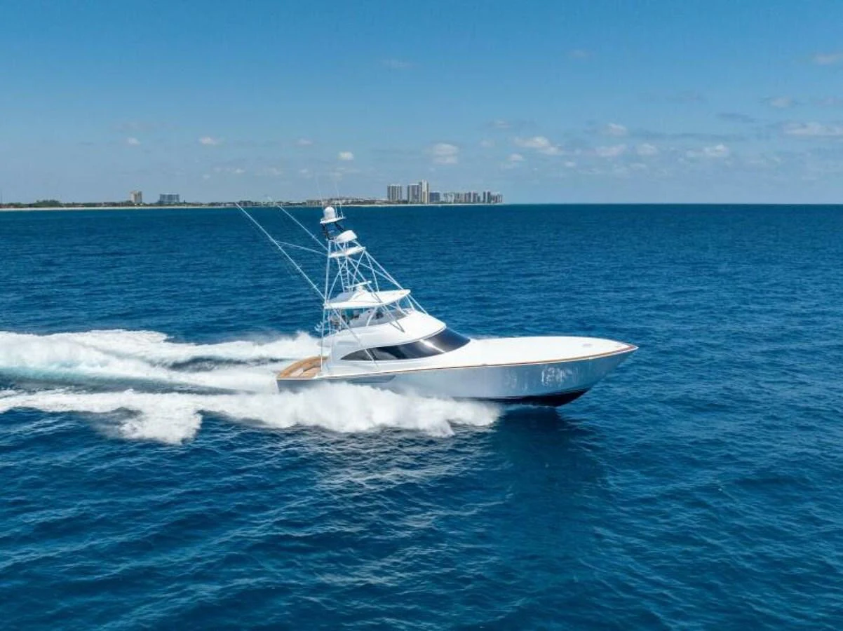 A sleek yacht cruises swiftly across the open sea under a clear blue sky. aboard 2027 VIKING 74C Yacht for Sale