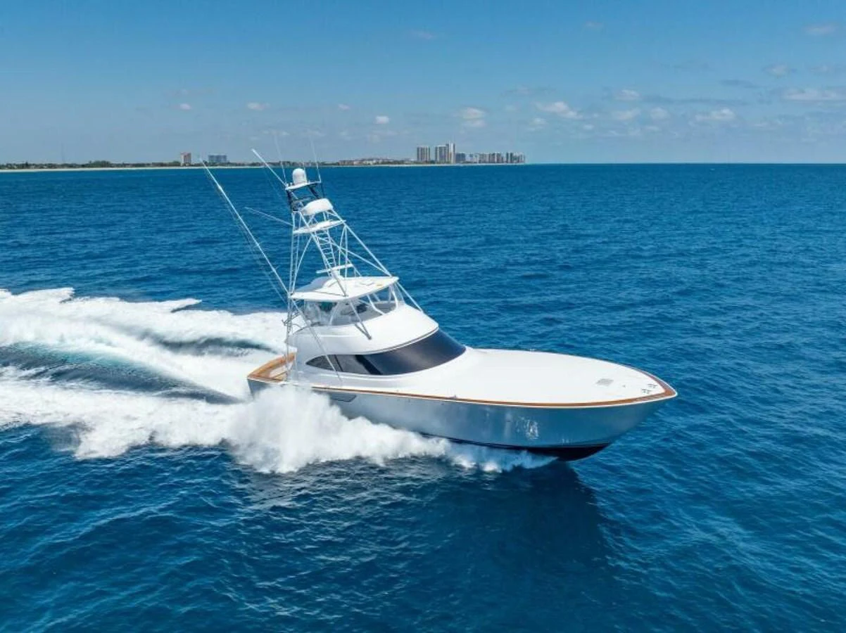 A sleek yacht cruises swiftly across the open sea under a clear blue sky. aboard 2027 VIKING 74C Yacht for Sale