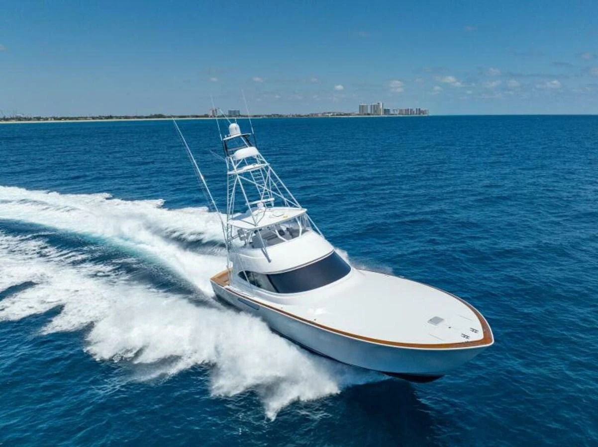 A sleek yacht cruises swiftly through the open sea under a clear blue sky. aboard 2027 VIKING 74C Yacht for Sale