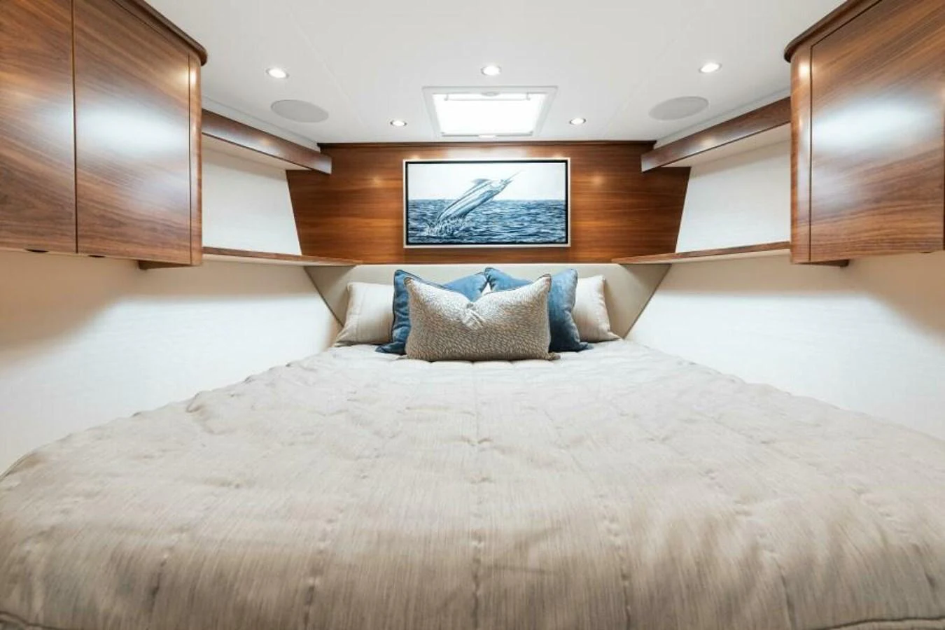 The stateroom features a cozy bed with elegant wood paneling and soft lighting. aboard 2027 VIKING 74C Yacht for Sale