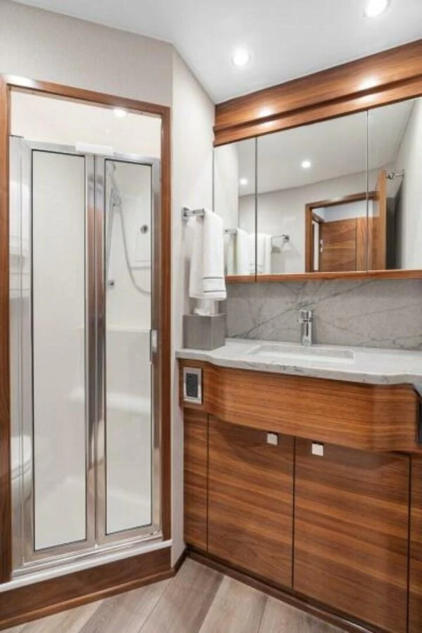 The yacht's bathroom features a sleek design with wood accents and modern fixtures. aboard 2027 VIKING 74C Yacht for Sale