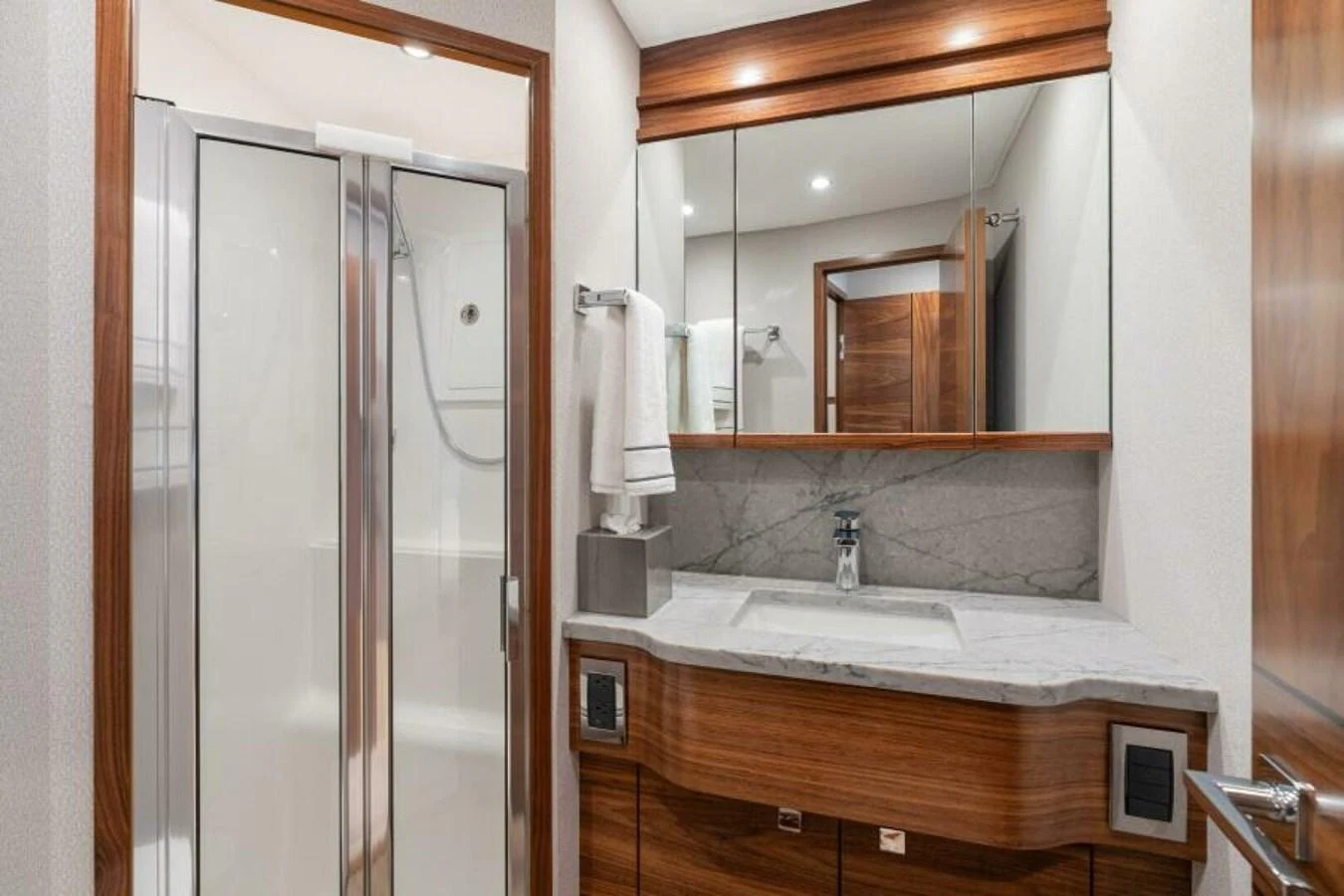 The yacht's bathroom features a sleek design with a modern shower and elegant wood accents. aboard 2027 VIKING 74C Yacht for Sale