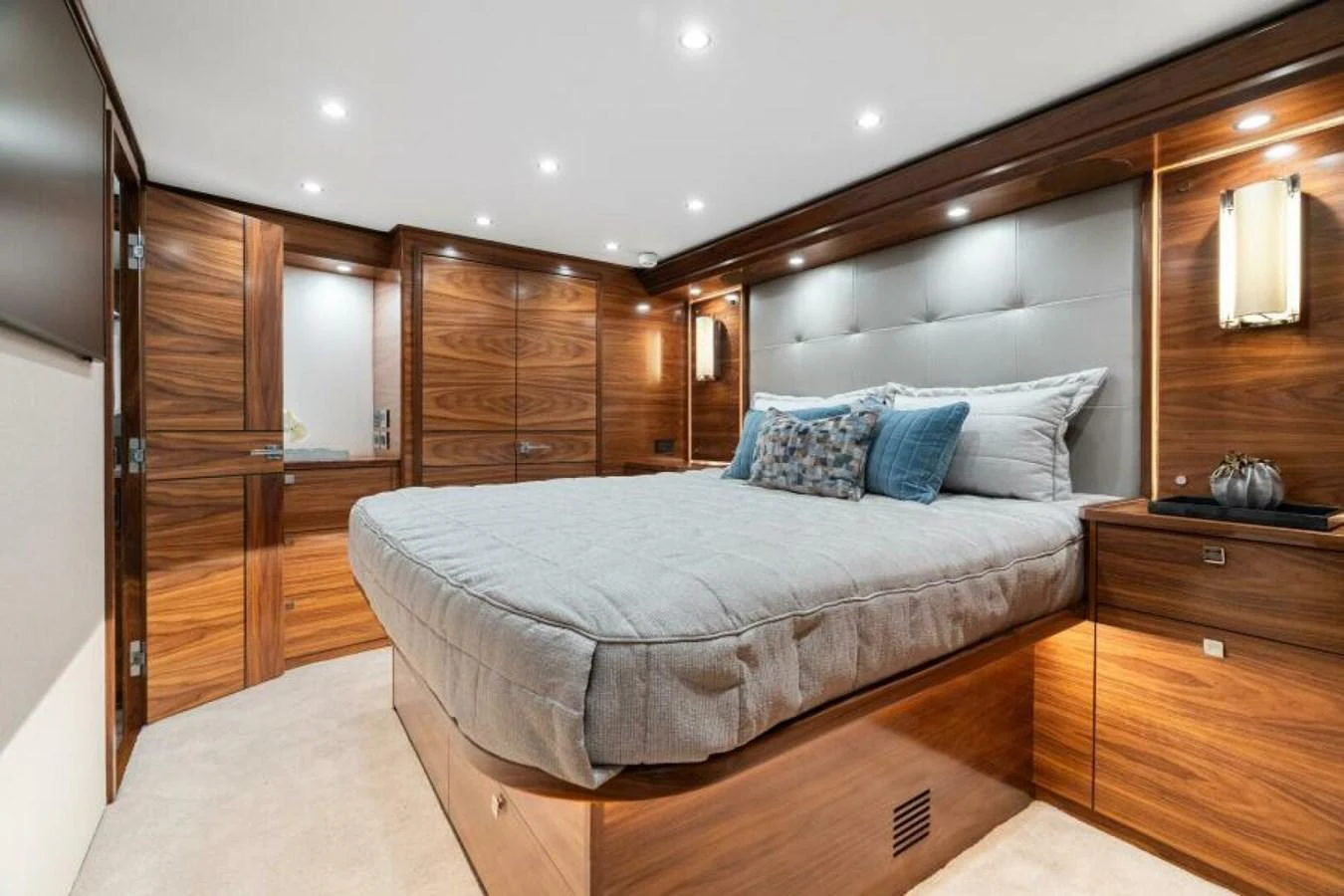 The stateroom features a luxurious bed with elegant wooden cabinetry and soft lighting. aboard 2027 VIKING 74C Yacht for Sale