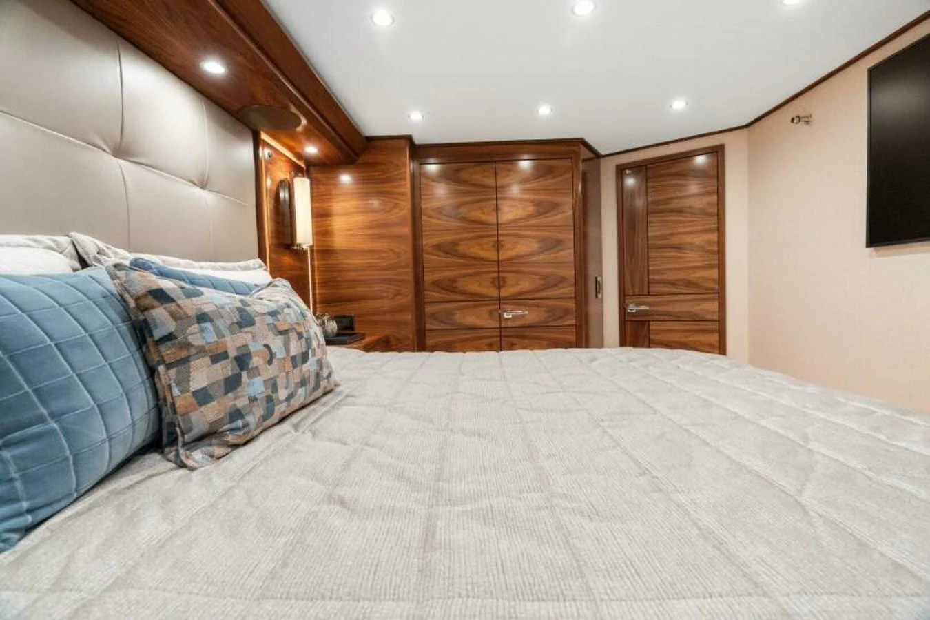 The stateroom features a luxurious bed with plush pillows and elegant wooden cabinetry. aboard 2027 VIKING 74C Yacht for Sale