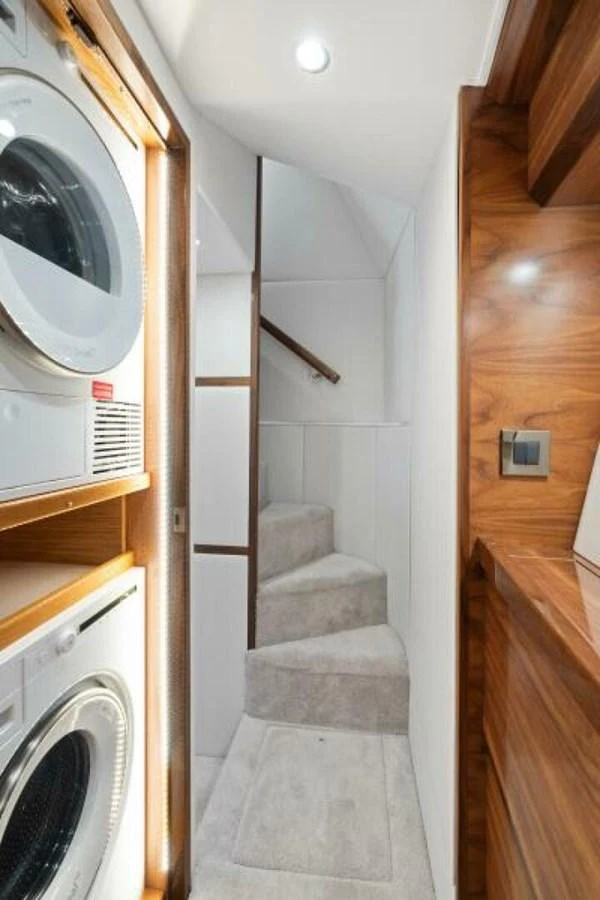 The image showcases a compact interior space with a staircase and laundry appliances. aboard 2027 VIKING 74C Yacht for Sale