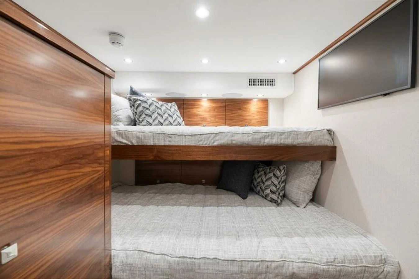 A cozy cabin with bunk beds and modern wooden finishes. aboard 2027 VIKING 74C Yacht for Sale