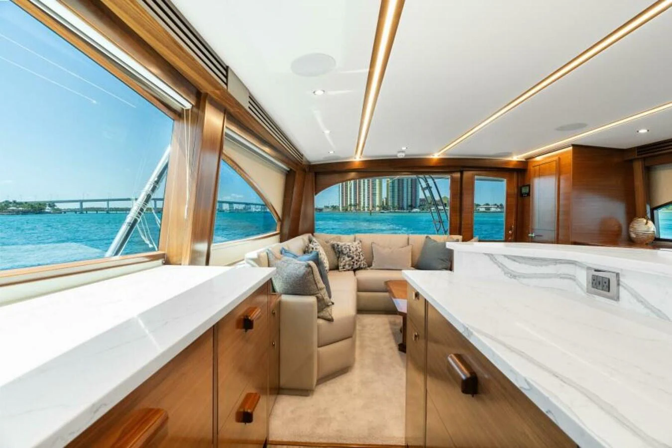 The salon offers a luxurious and spacious area with large windows providing stunning views of the water. aboard 2027 VIKING 74C Yacht for Sale
