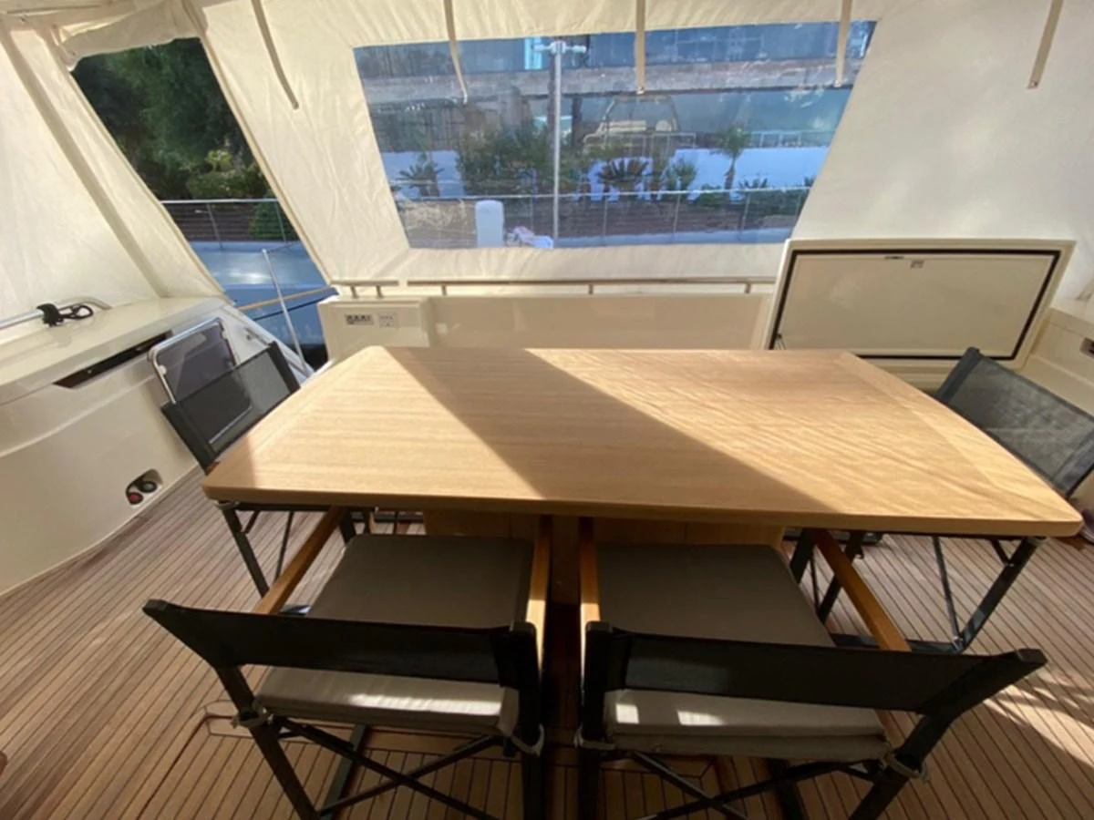 The aft deck features a spacious dining area with a wooden table and comfortable chairs, perfect for alfresco meals. aboard LA LUNA Yacht for Sale