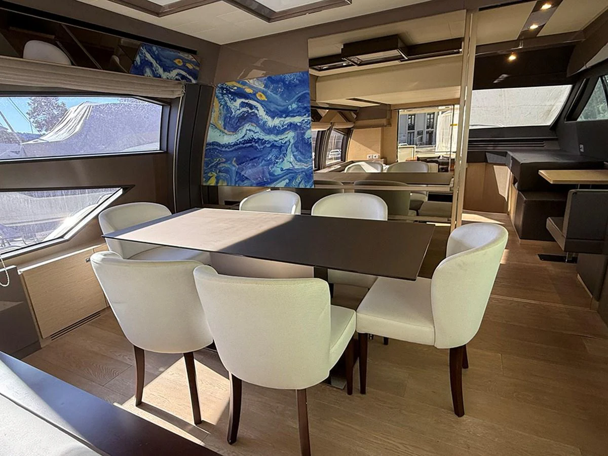 The yacht's dining area features a modern table surrounded by elegant white chairs, complemented by large windows and contemporary artwork. aboard LA LUNA Yacht for Sale