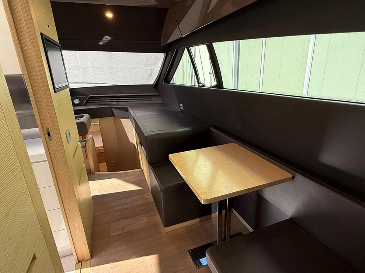 The yacht's saloon features a cozy dining area with a table and cushioned seating, bathed in natural light from large windows. aboard LA LUNA Yacht for Sale