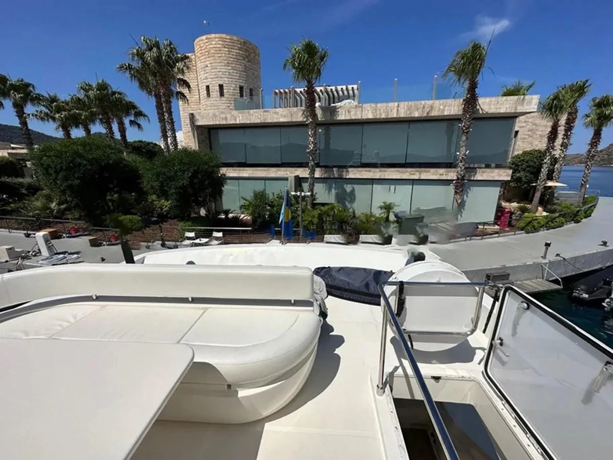The yacht's flybridge offers a comfortable seating area with views of the surrounding architecture and palm trees. aboard LA LUNA Yacht for Sale
