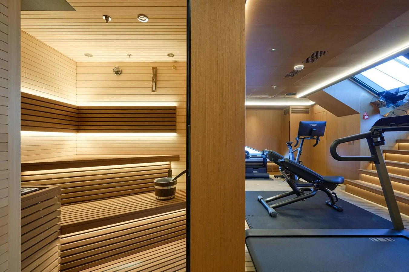The yacht features a luxurious gym and sauna area with modern equipment and wooden finishes. aboard LOEWE Yacht for Sale