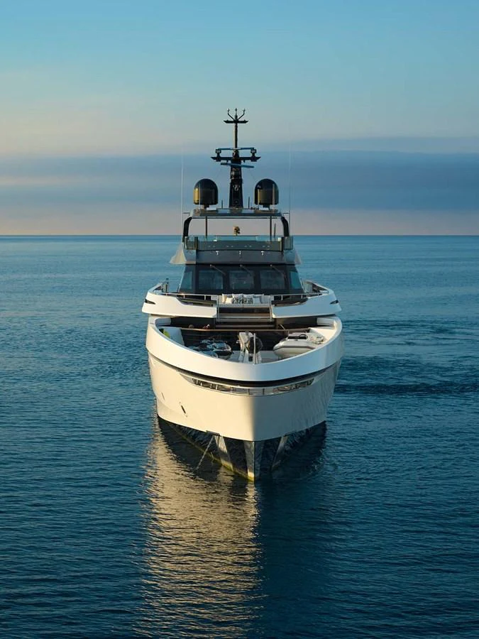 A sleek and modern yacht is seen head-on, cruising on calm waters during a serene sunset. aboard LOEWE Yacht for Sale