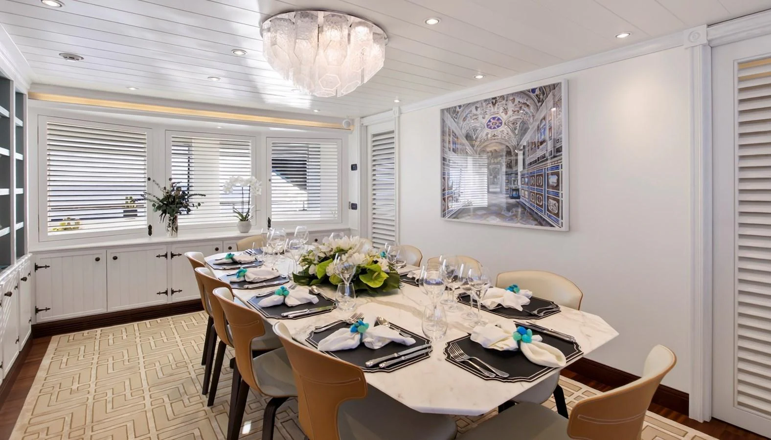 The yacht's dining area features an elegant table setting with a modern chandelier and stylish decor. aboard LADY TRUDY Yacht for Sale