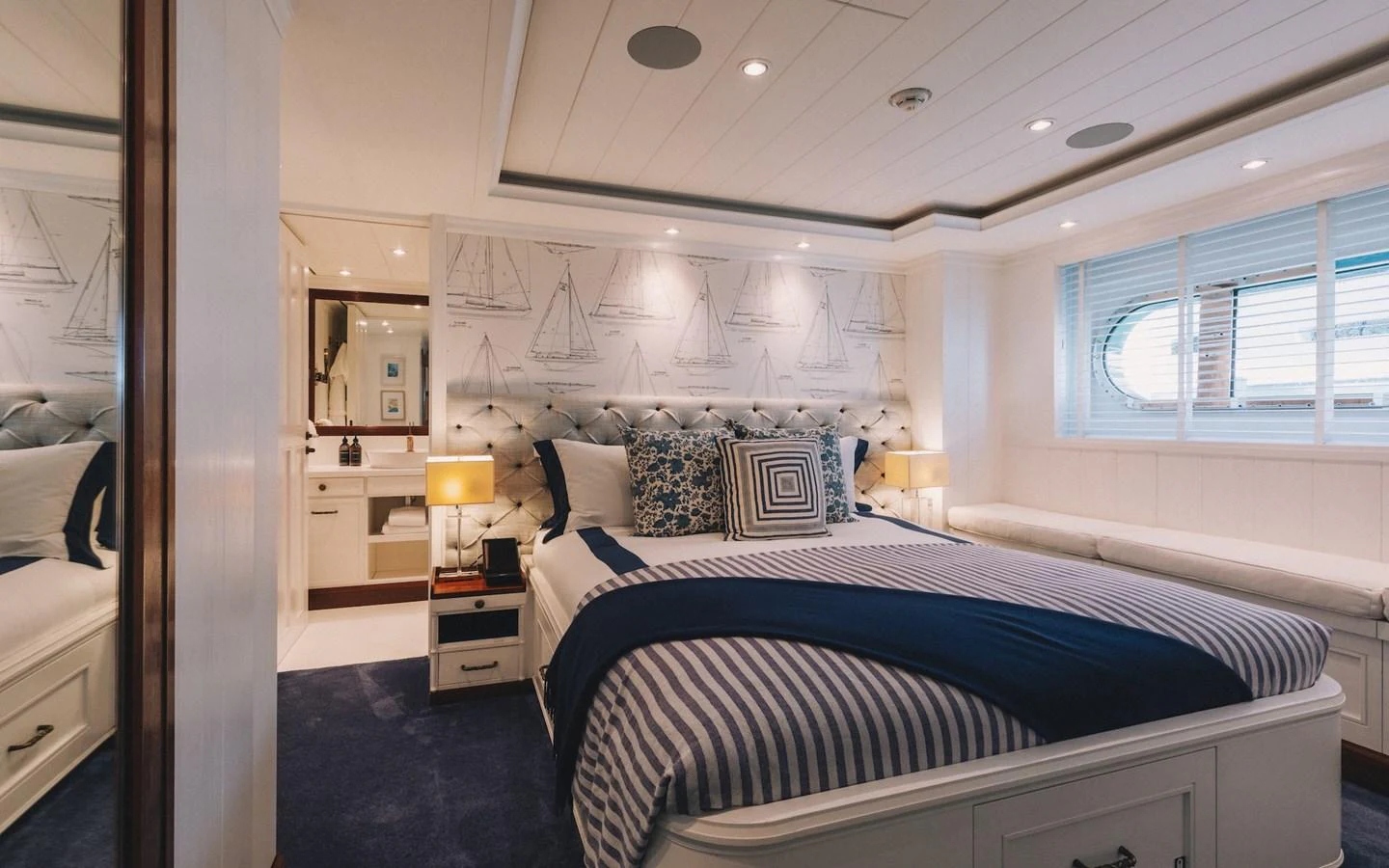 A luxurious stateroom featuring a plush bed with nautical-themed decor and ample natural light. aboard LADY TRUDY Yacht for Sale