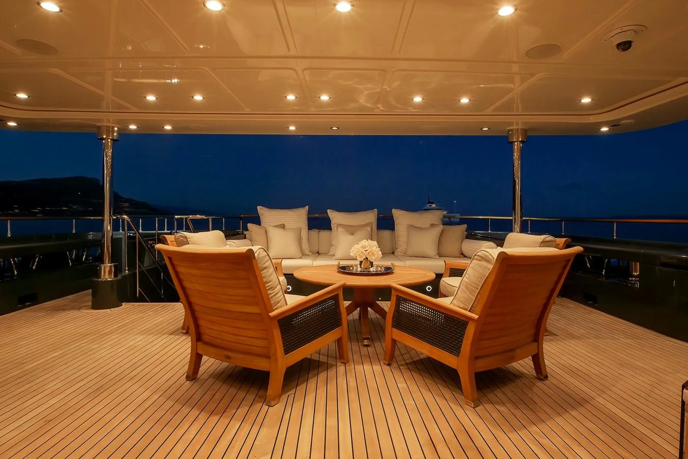 The aft deck features a cozy seating area with wooden chairs and a round table, perfect for evening relaxation. aboard LADY TRUDY Yacht for Sale